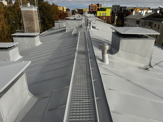 Inkoonkadun vesikaton huoltomaalaus: harmaa peltikate, kattosilta ja piippujen pellitykset Helsingissä.